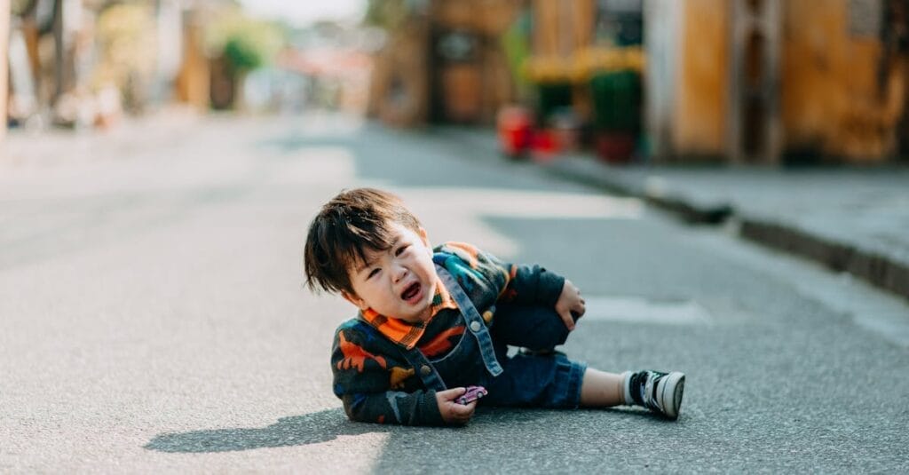 A child sitting on an empty street, expressing sadness and frustration.