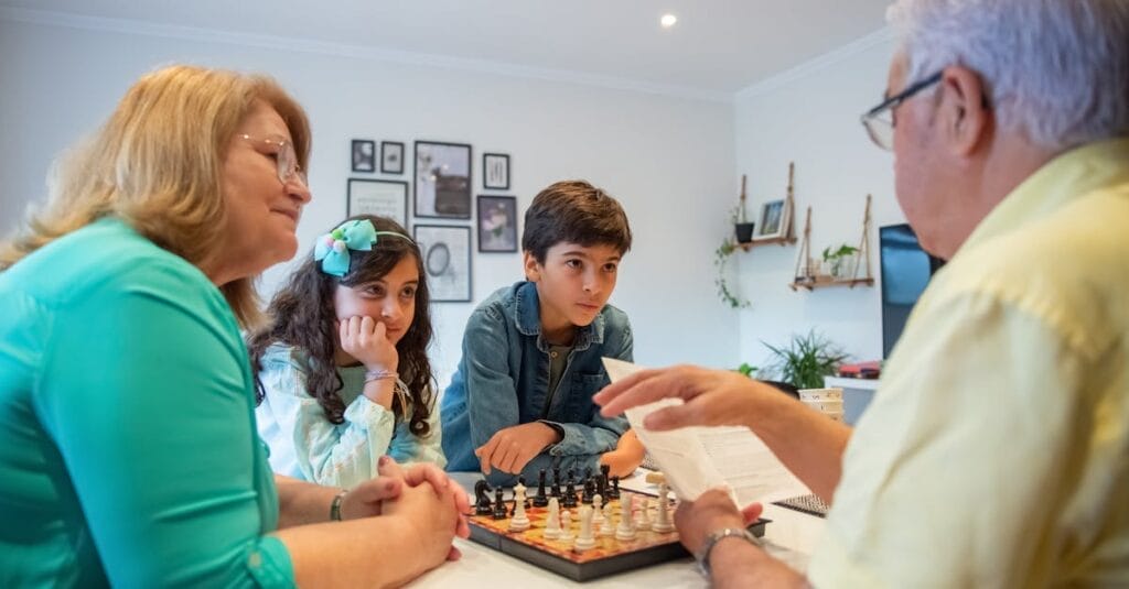 Family gathering indoors for chess and learning, capturing generations sharing moments together.