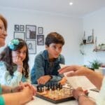 Family gathering indoors for chess and learning, capturing generations sharing moments together.