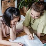 A mother helping her daughter with homework in a cozy home environment, fostering learning.