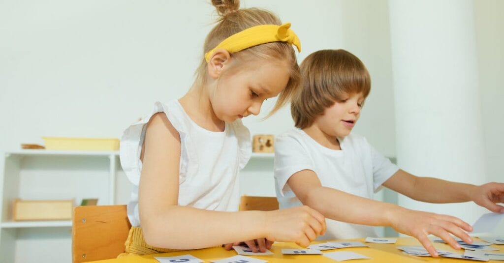 Two young children engaged in a fun learning activity indoors, focusing on letters.