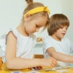 Two young children engaged in a fun learning activity indoors, focusing on letters.