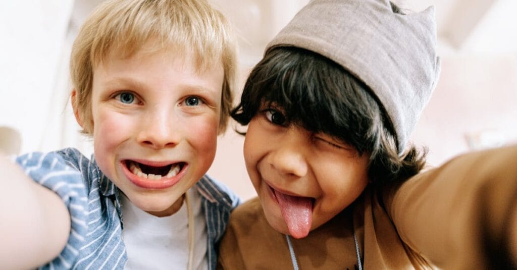 Two joyful children taking a fun selfie, capturing their silly expressions indoors.