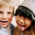 Two joyful children taking a fun selfie, capturing their silly expressions indoors.