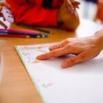 Children engage in a colorful art activity, drawing with pencils and markers in a classroom setting.
