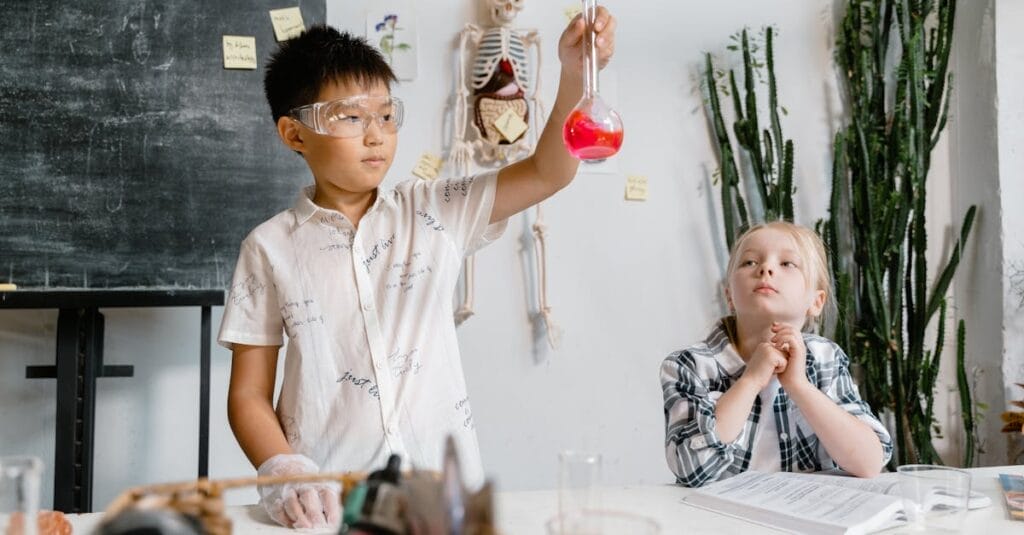 Two children experimenting with chemicals in a classroom, focusing on learning.