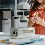 Young girl exploring science with a microscope and lab equipment indoors.