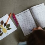 Top view of child engaged in a word puzzle, next to a handmade leaf art.