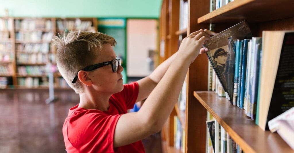 A young boy wearing glasses selects a book from a library bookshelf, emphasizing education and reading.