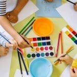 Kids enjoying watercolor painting indoors, fostering creativity and learning.