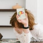 Child focused on a colorful chameleon flash card during an educational game indoors.