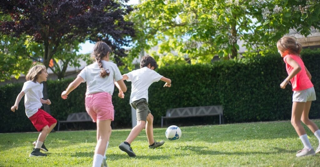 Group of kids enjoying a football game on a sunny day in the park.