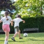 Group of kids enjoying a football game on a sunny day in the park.