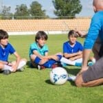 Children gather for a soccer coaching session on a sunny day in Portugal.