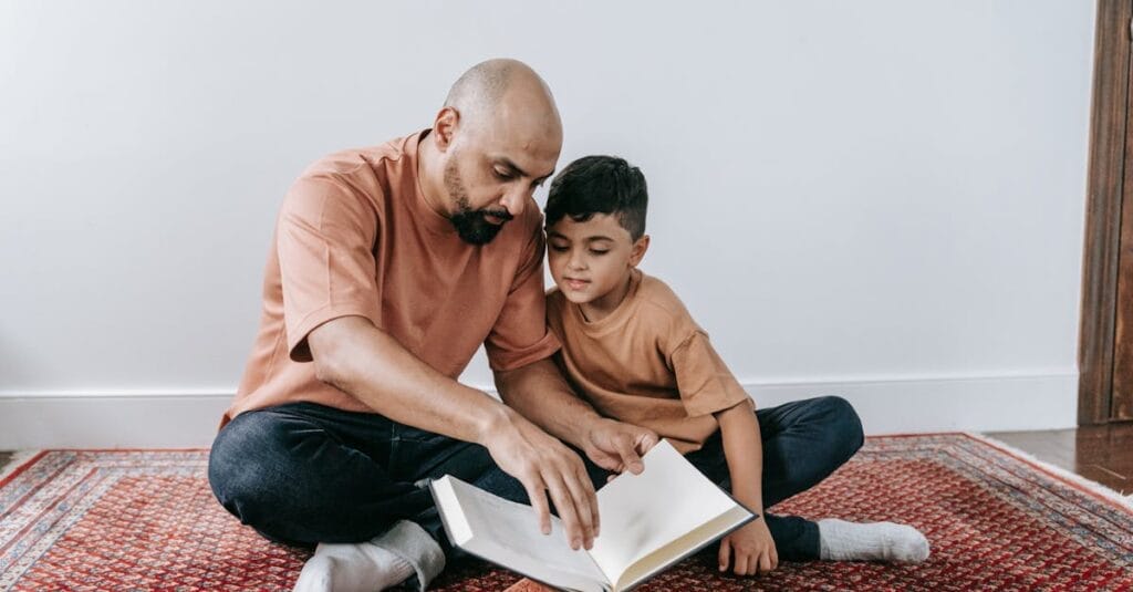 A father and son sitting on a rug, bonding over reading indoors.