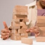 A child thoughtfully stacks wooden blocks with words like 'depression' and 'kindness.'