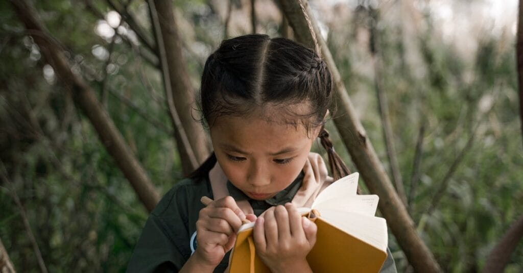 Young girl scout in forest taking notes in a notebook.