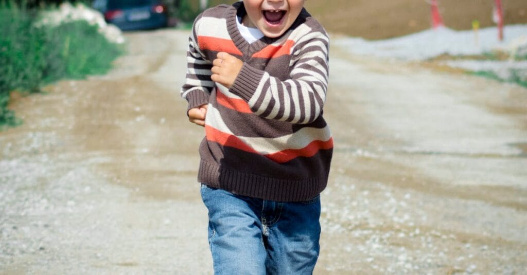 A young boy joyfully runs down a path, showcasing playful energy in a Czech outdoor setting.