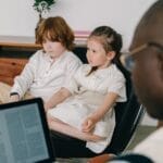 Therapist working with two children in an indoor therapy session, focusing on mental health.