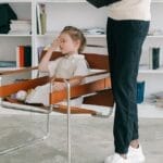 A child in a therapy session with a therapist holding a clipboard.